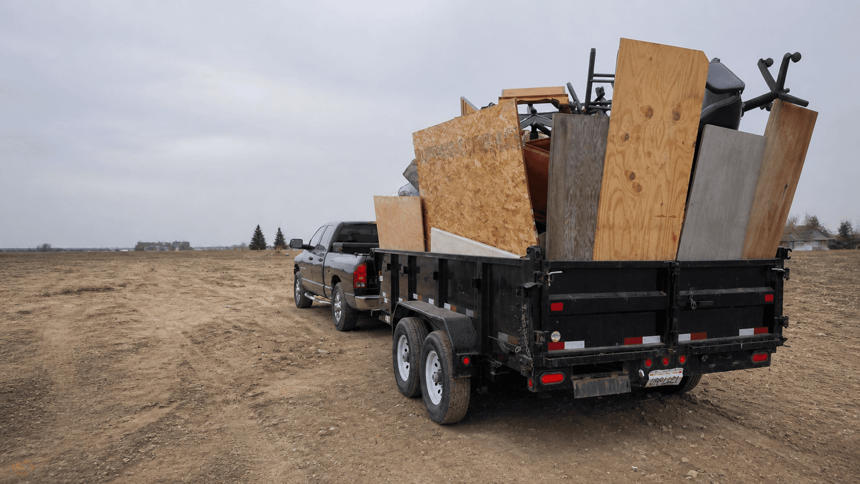 Black dump trailer and pickup loaded for a San Diego junk removal job